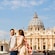 A couple holding hands and walking with Saint Peter’s Basilica in the background